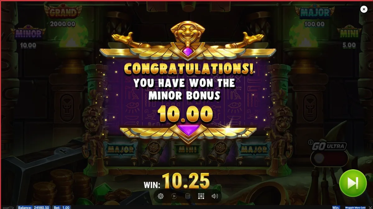Tampilan visual slot Wrappin’ More Gold dengan karakter mumi yang ramah dan latar belakang Mesir kuno.
